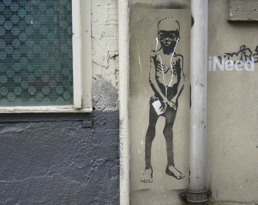 Street art med av offer for sult med iPod og teksten iNeed